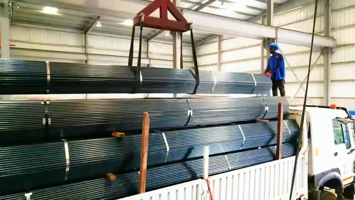 Crane loading pipe onto a delivery truck